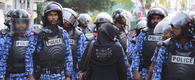 Una sostenitrice dell'opposizione maldiviana si trova di fronte alla polizia durante una protesta. Credits to: AP.