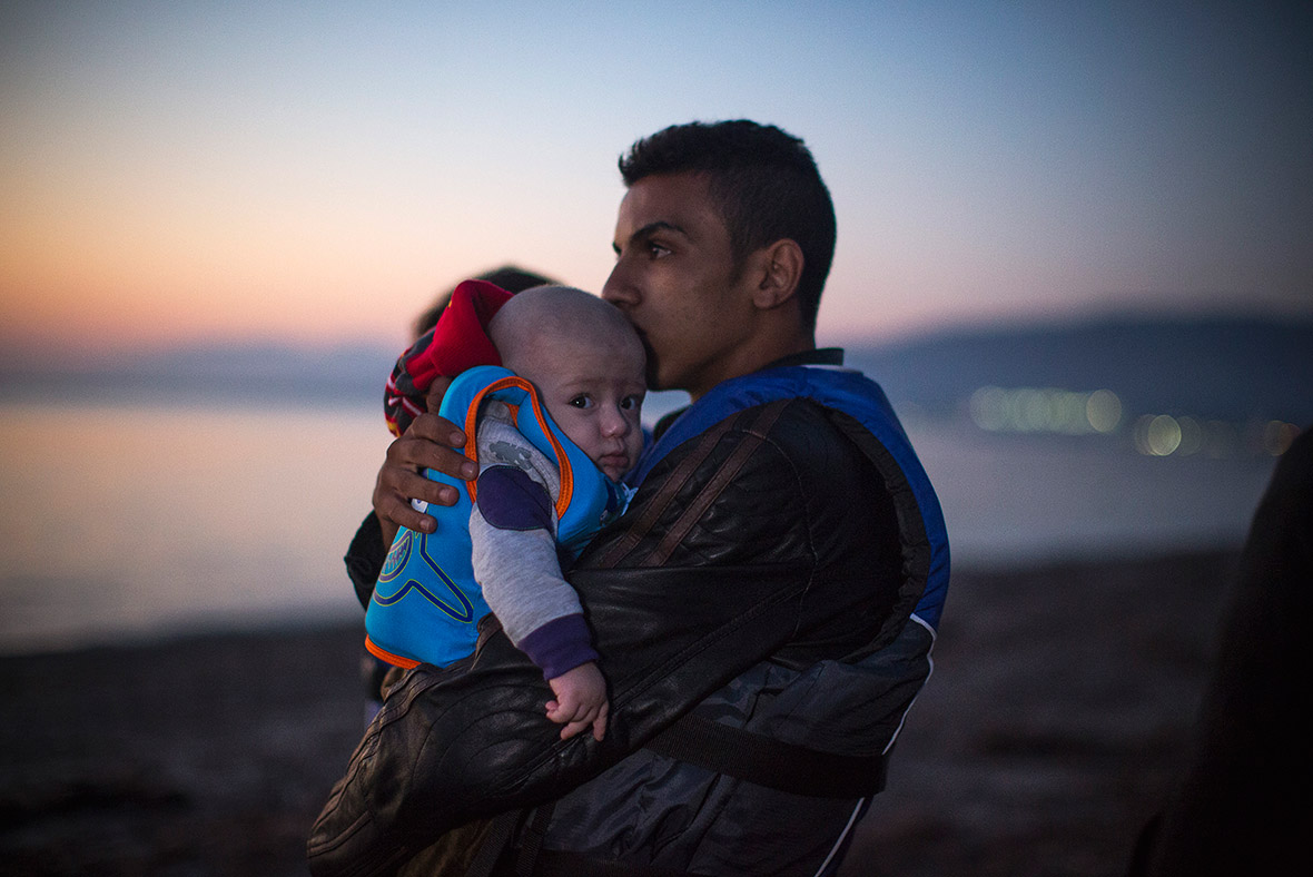 Un rifugiato siriano bacia il suo bambino all'arrivo a Kos (Grecia).