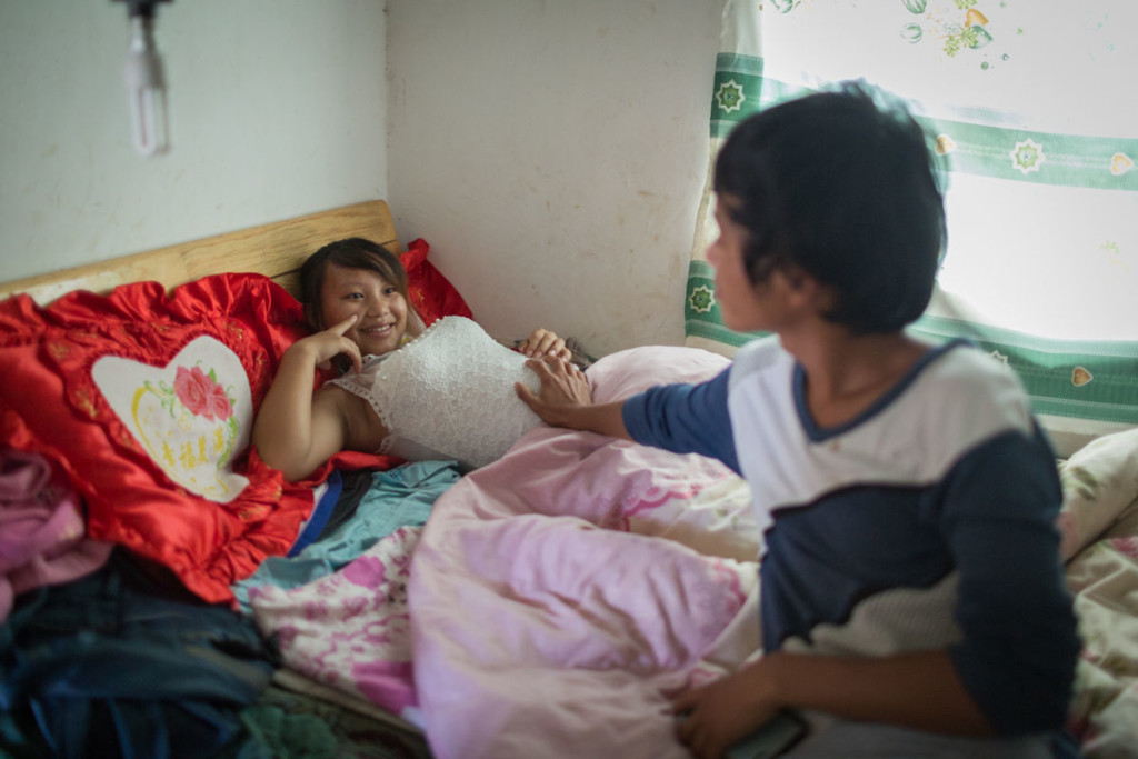 Xiao Wen, di 18 anni, accarezza la pancia di sua moglie Xiao Jie, 13 anni, circa al sesto mese di gravidanza, nella loro casa nel villaggio di Tangzibian, Cina – 3 novembre 2014 - © Mury Xiao