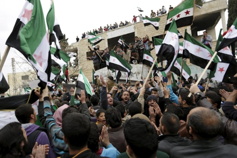 I residenti di Maarat al-Nouman (Idlib) protestano contro il regime siriano sventolando la bandiera siriana in vigore prima della salita degli Assad al potere, cioè quella dell'indipendenza, adottata subito dopo la fine del domino francese, 4/03/2016. Credits to: Khalil Ashawi/Reuters