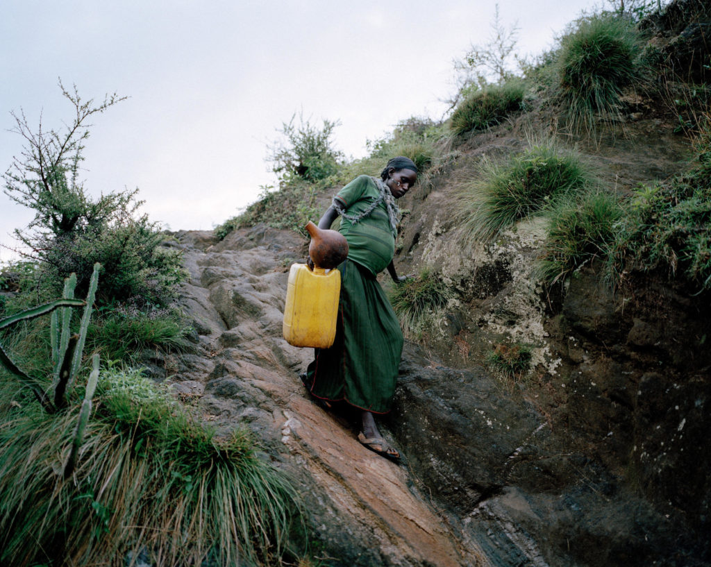 Uchiya, 29, eight months pregnant, carries an empty jerry can from her mountaintop home to a source of water below. She'll fill it with five gallons and then climb back up. In sub-Saharan Africa, women spent 40 billion hours a year collecting water.