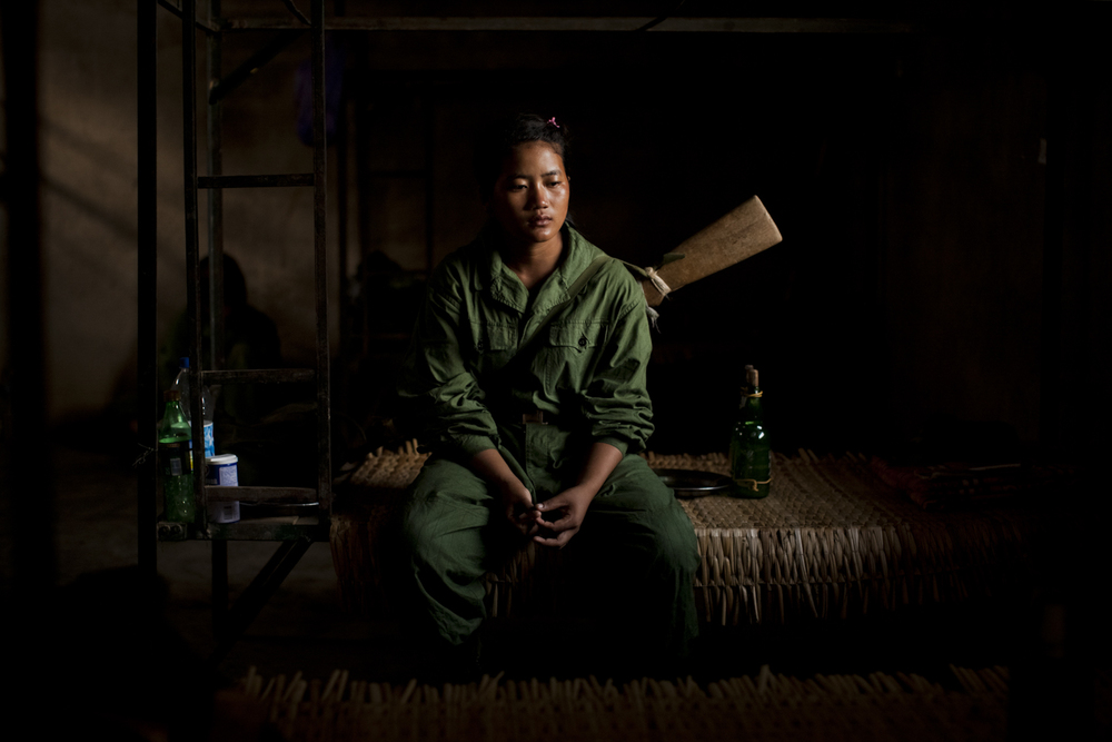 Le lacrime scendono sul viso di una ragazza seduta sul suo letto, appena dopo l'addestramento militare del mattino, nel quartier generale della quinta brigata del KIA, fuori da Laiza, nello stato del Kachin, Myanmar, maggio 2013. Le donne arruolate nell'esercito guadagnano 10.000 Kyat al mese (circa 10 dollari) e spesso, dopo essersi arruolate, possono andarsene soltanto per sposarsi © Adriane Ohanesian
