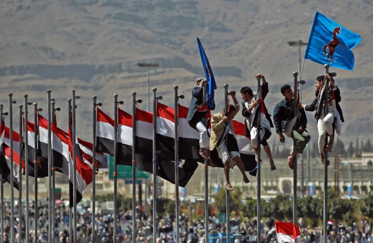 Sanaa, sostenitori di Ali Abdullah Saleh si arrampicano in occasione di una celebrazione, sulle aste che sostengono la bandiera nazionale (Mohammed Huwais/Getty Images)