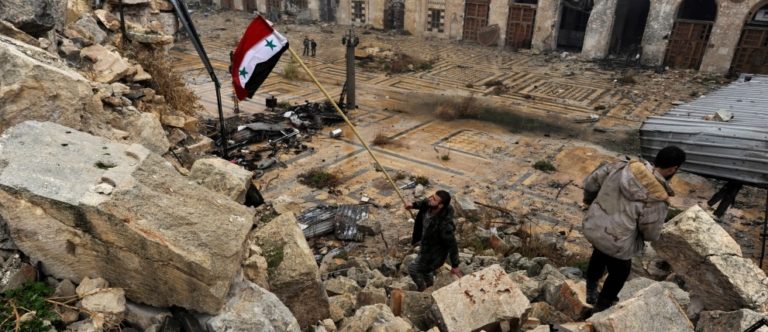 Un soldato siriano sventola la bandiera nazionale sulle macerie della moschea degli Omayyadi ad Aleppo – credits: Omar Sanadiki / Reuters